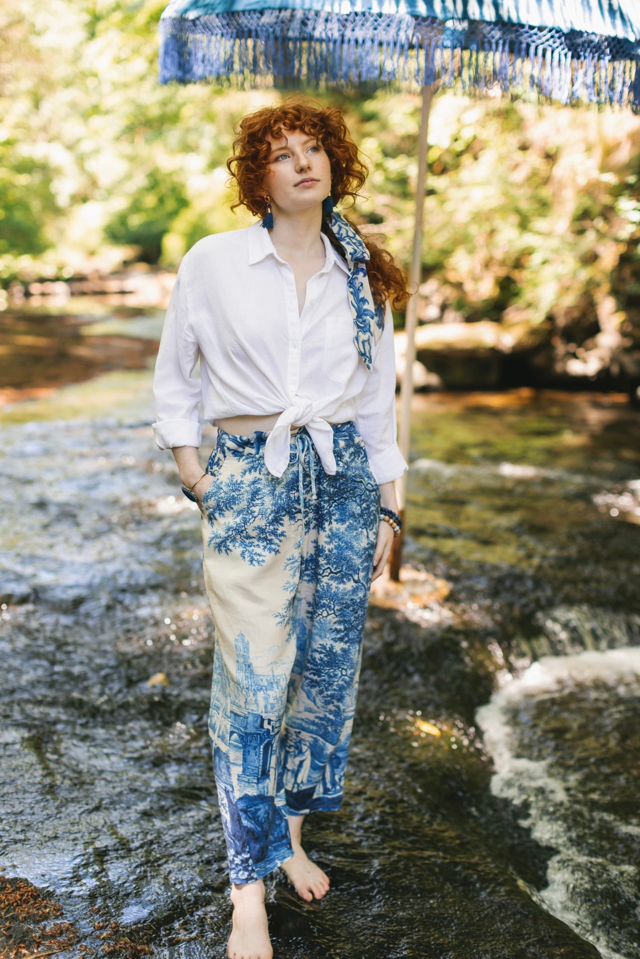 Model wearing Let the Light In linen Artist Pant featuring print of Delft blue and white landscape pottery, and positive message of light and hope - Market of Stars