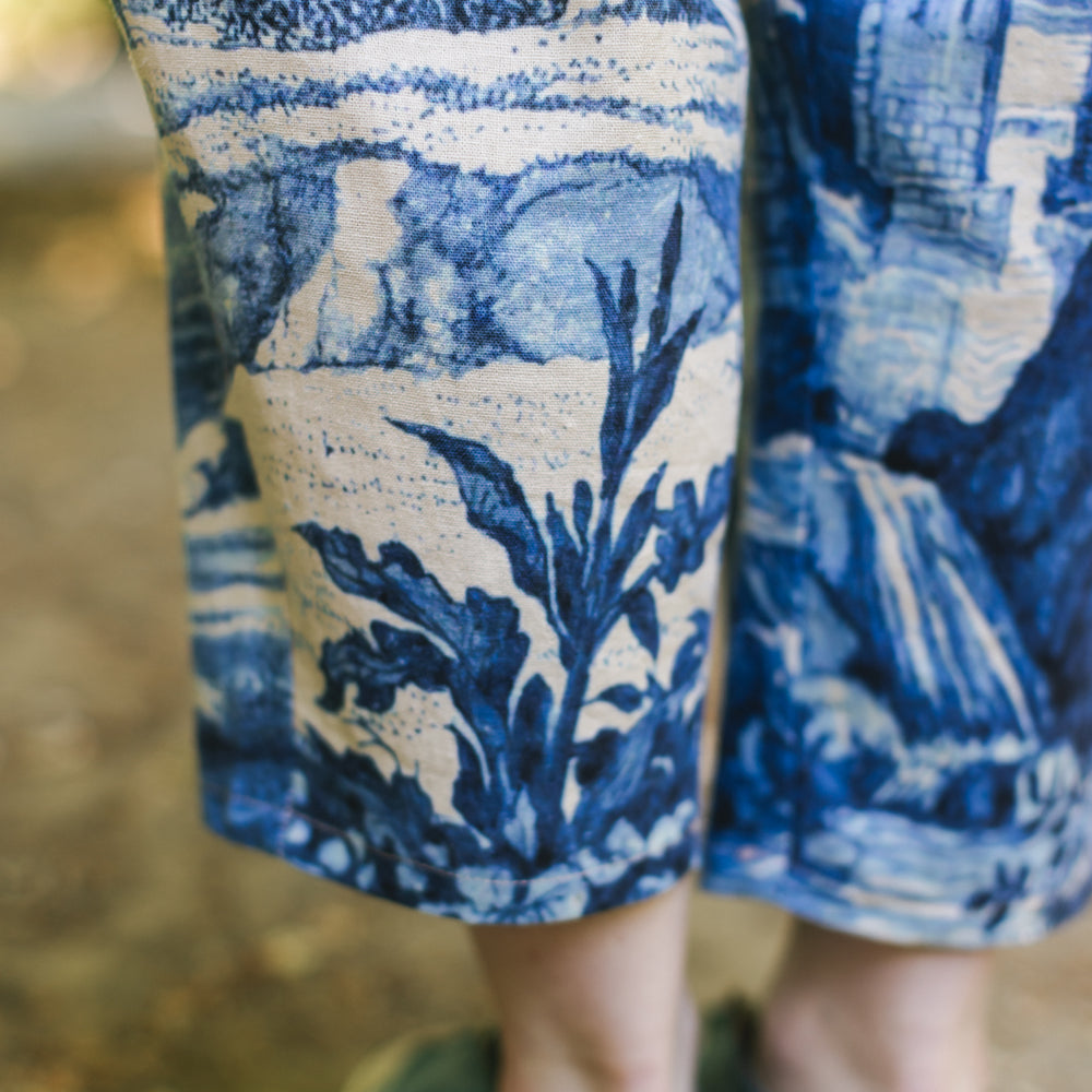 
                  
                    Model wearing Let the Light In linen Artist Pant featuring print of Delft blue and white landscape pottery, and positive message of light and hope - Market of Stars
                  
                