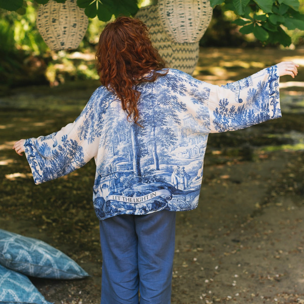 
                  
                    Model wearing Let the Light In cropped Pixie duster featuring print of Delft blue and white landscape pottery, and positive message of light and hope - Market of Stars
                  
                