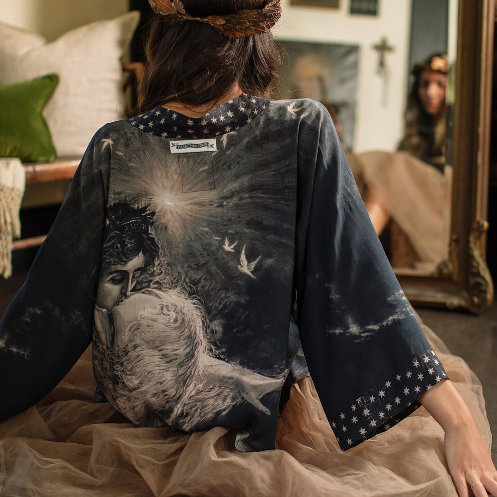 Model wearing Love Conquers All Kimono featuring an 1800s heart-shaped embrace, doves, crescent moon, and the words Amor Vincit Omnia – Market of Stars.