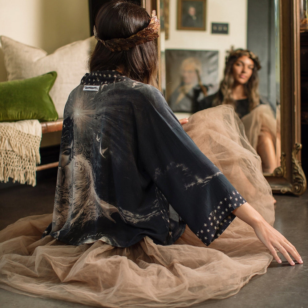 
                  
                    Model wearing Love Conquers All Kimono featuring an 1800s heart-shaped embrace, doves, crescent moon, and the words Amor Vincit Omnia – Market of Stars.
                  
                