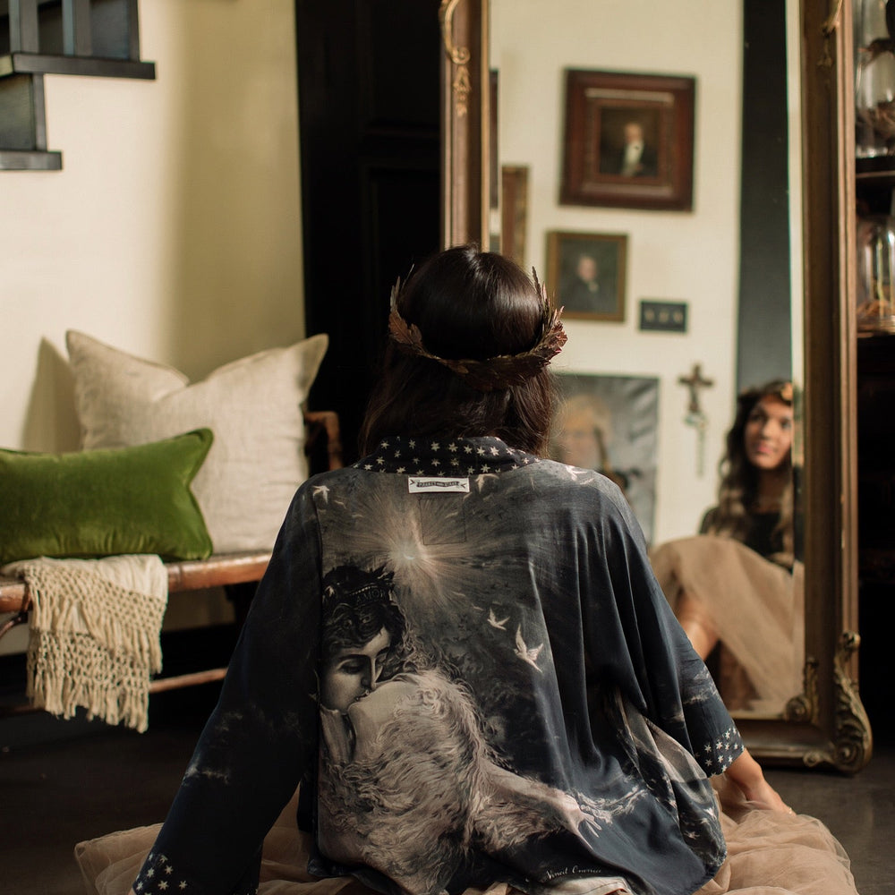 
                  
                    Model wearing Love Conquers All Kimono featuring an 1800s heart-shaped embrace, doves, crescent moon, and the words Amor Vincit Omnia – Market of Stars.
                  
                