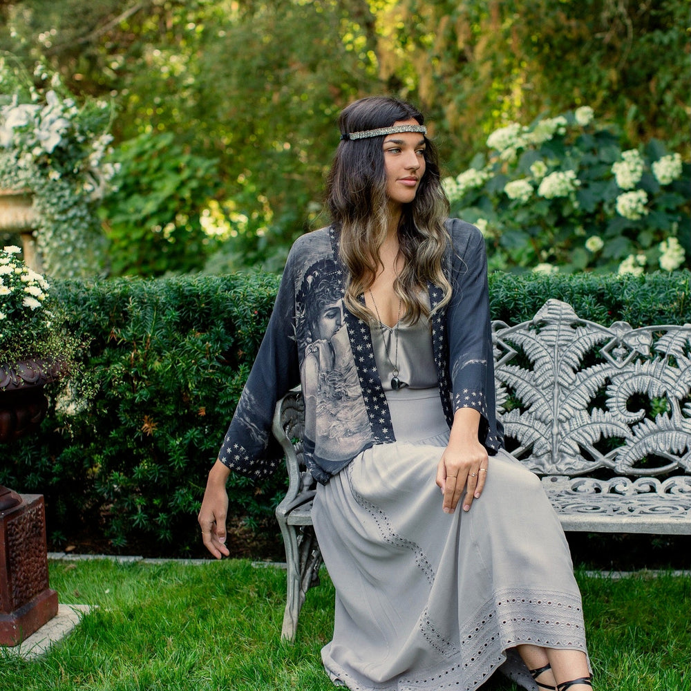 
                  
                    Model wearing Love Conquers All Kimono featuring an 1800s heart-shaped embrace, doves, crescent moon, and the words Amor Vincit Omnia – Market of Stars.
                  
                