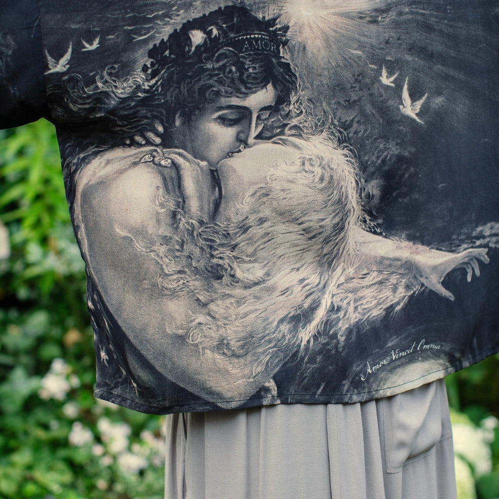 
                  
                    Model wearing Love Conquers All Kimono featuring an 1800s heart-shaped embrace, doves, crescent moon, and the words Amor Vincit Omnia – Market of Stars.
                  
                
