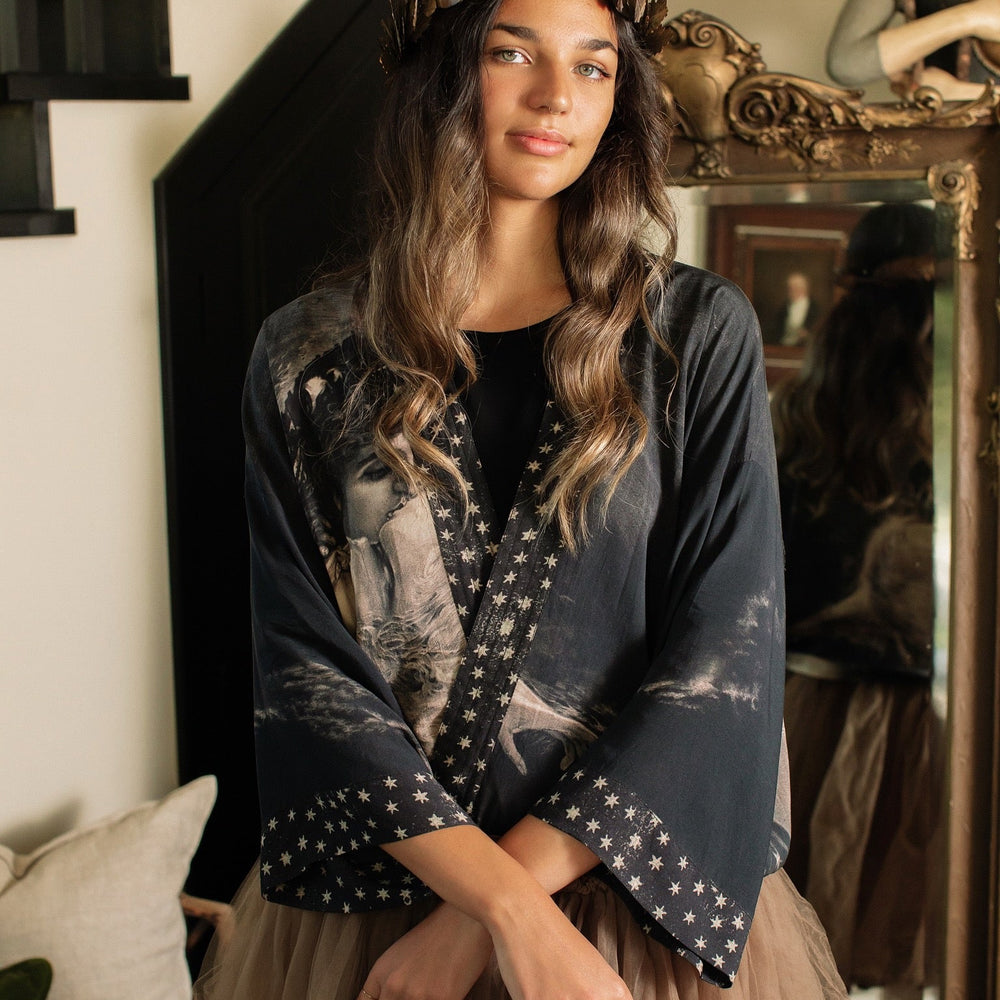 
                  
                    Model wearing Love Conquers All Kimono featuring an 1800s heart-shaped embrace, doves, crescent moon, and the words Amor Vincit Omnia – Market of Stars.
                  
                