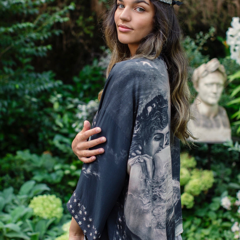 
                  
                    Model wearing Love Conquers All Kimono featuring an 1800s heart-shaped embrace, doves, crescent moon, and the words Amor Vincit Omnia – Market of Stars.
                  
                