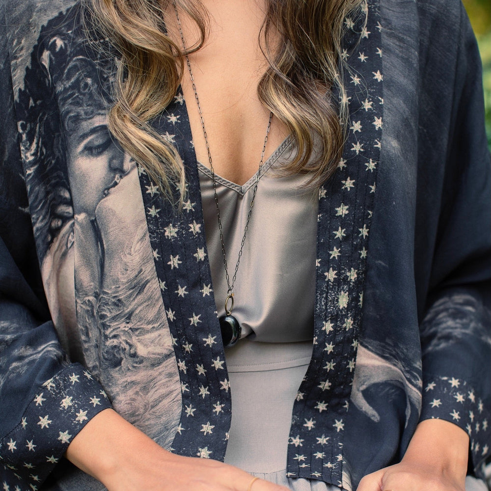 
                  
                    Model wearing Love Conquers All Kimono featuring an 1800s heart-shaped embrace, doves, crescent moon, and the words Amor Vincit Omnia – Market of Stars.
                  
                
