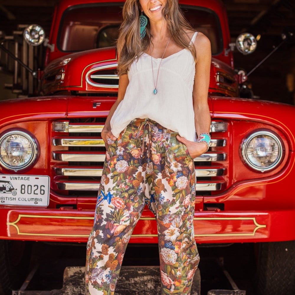 
                  
                    Model wearing linen blend artist pants with 1854 floral art, heart-in-hand symbol, and “Love one another” handwritten script – Market of Stars.
                  
                