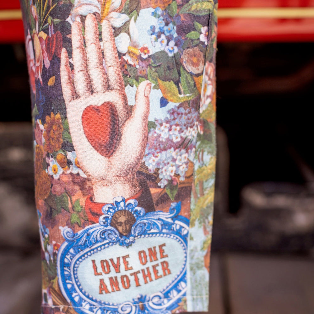 
                  
                    Model wearing linen blend artist pants with 1854 floral art, heart-in-hand symbol, and “Love one another” handwritten script – Market of Stars.
                  
                