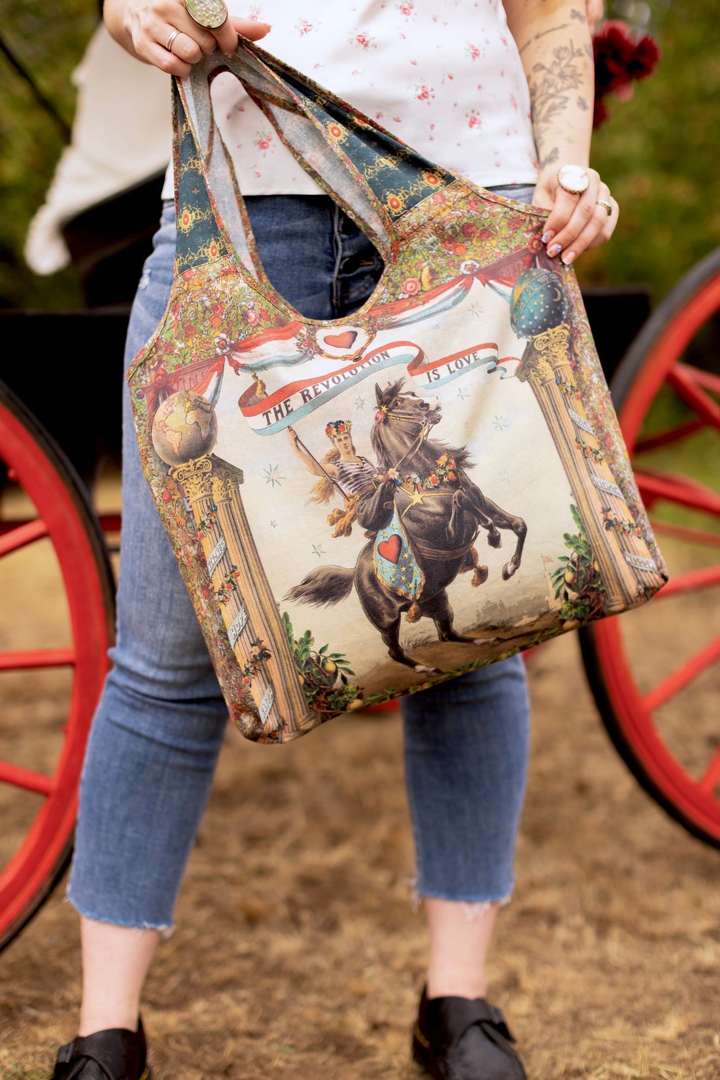 Model carrying a linen tote bag ft. a woman astride a rearing horse, soft vintage florals, rosettes and lithographs from the 1800's - Market of Stars