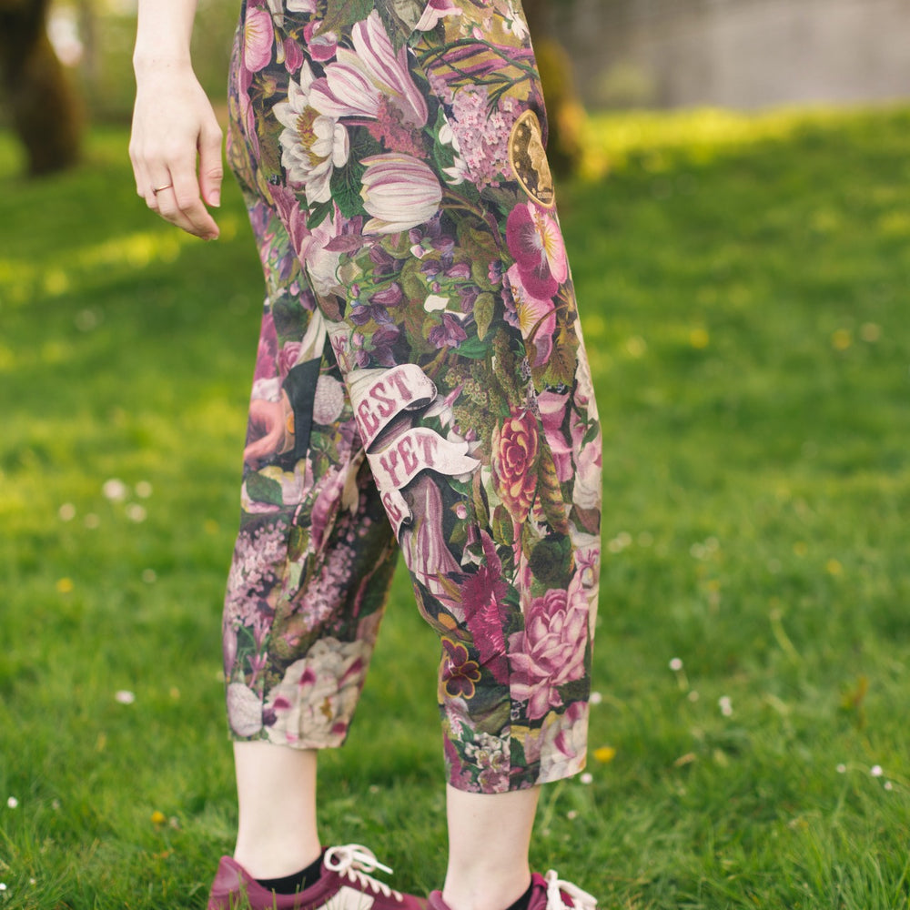 Model wearing linen blend artist pants featuring antique wishbone–Victorian coin–evening star–dandelion art and “Wish with Me” banner on floral background – Market of Stars