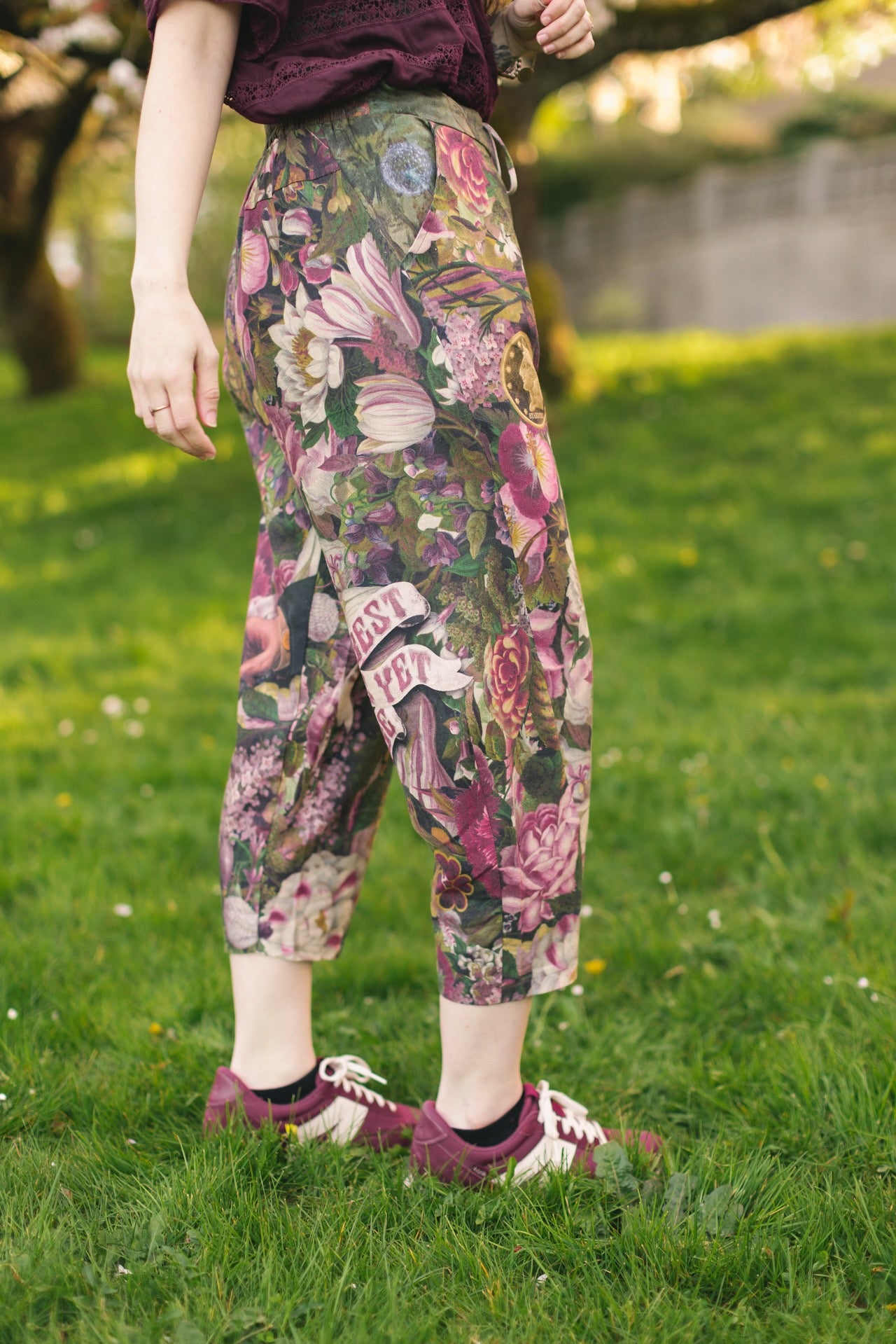 Model wearing linen blend artist pants featuring antique wishbone–Victorian coin–evening star–dandelion art and “Wish with Me” banner on floral background – Market of Stars