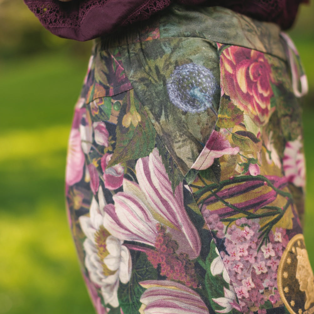 
                  
                    Model wearing linen blend artist pants featuring antique wishbone–Victorian coin–evening star–dandelion art and “Wish with Me” banner on floral background – Market of Stars
                  
                