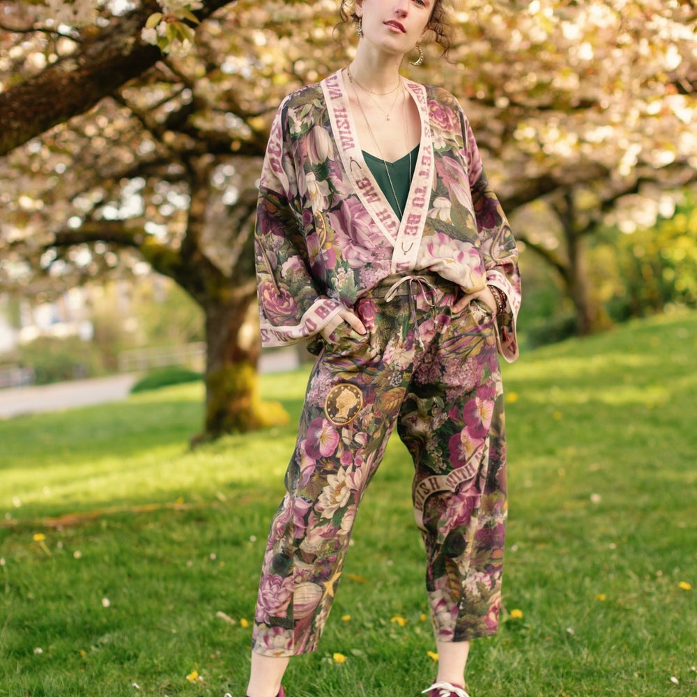 
                  
                    Model wearing linen blend artist pants featuring antique wishbone–Victorian coin–evening star–dandelion art and “Wish with Me” banner on floral background – Market of Stars
                  
                