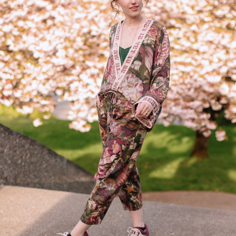 
                  
                    Model wearing linen blend artist pants featuring antique wishbone–Victorian coin–evening star–dandelion art and “Wish with Me” banner on floral background – Market of Stars
                  
                