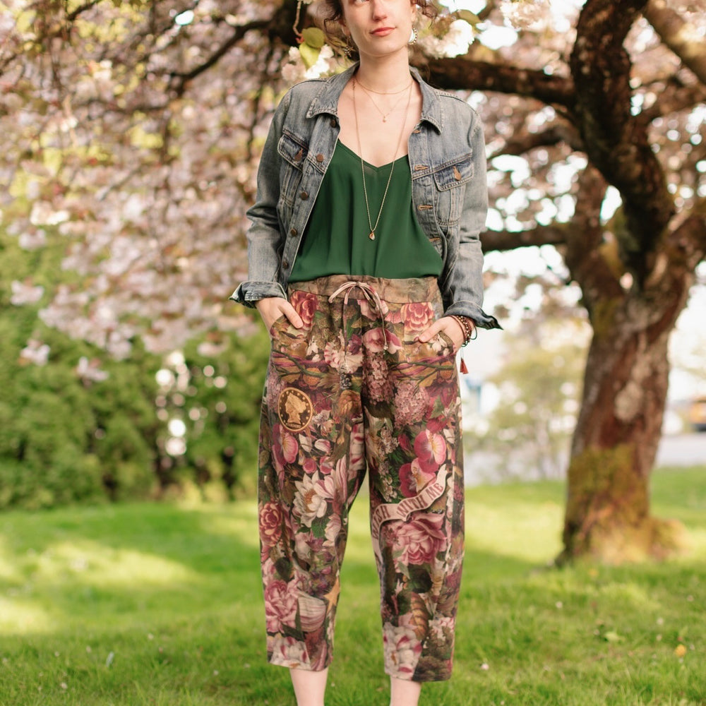 
                  
                    Model wearing linen blend artist pants featuring antique wishbone–Victorian coin–evening star–dandelion art and “Wish with Me” banner on floral background – Market of Stars
                  
                