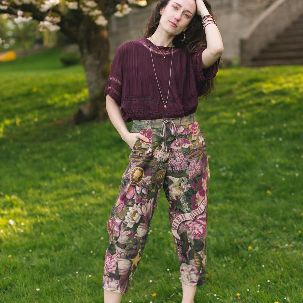 
                  
                    Model wearing linen blend artist pants featuring antique wishbone–Victorian coin–evening star–dandelion art and “Wish with Me” banner on floral background – Market of Stars
                  
                