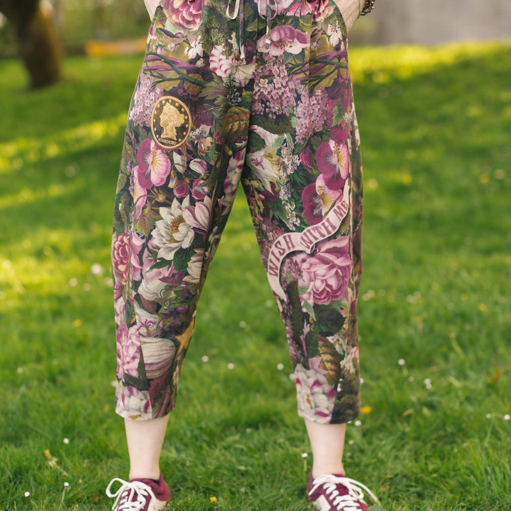
                  
                    Model wearing linen blend artist pants featuring antique wishbone–Victorian coin–evening star–dandelion art and “Wish with Me” banner on floral background – Market of Stars
                  
                
