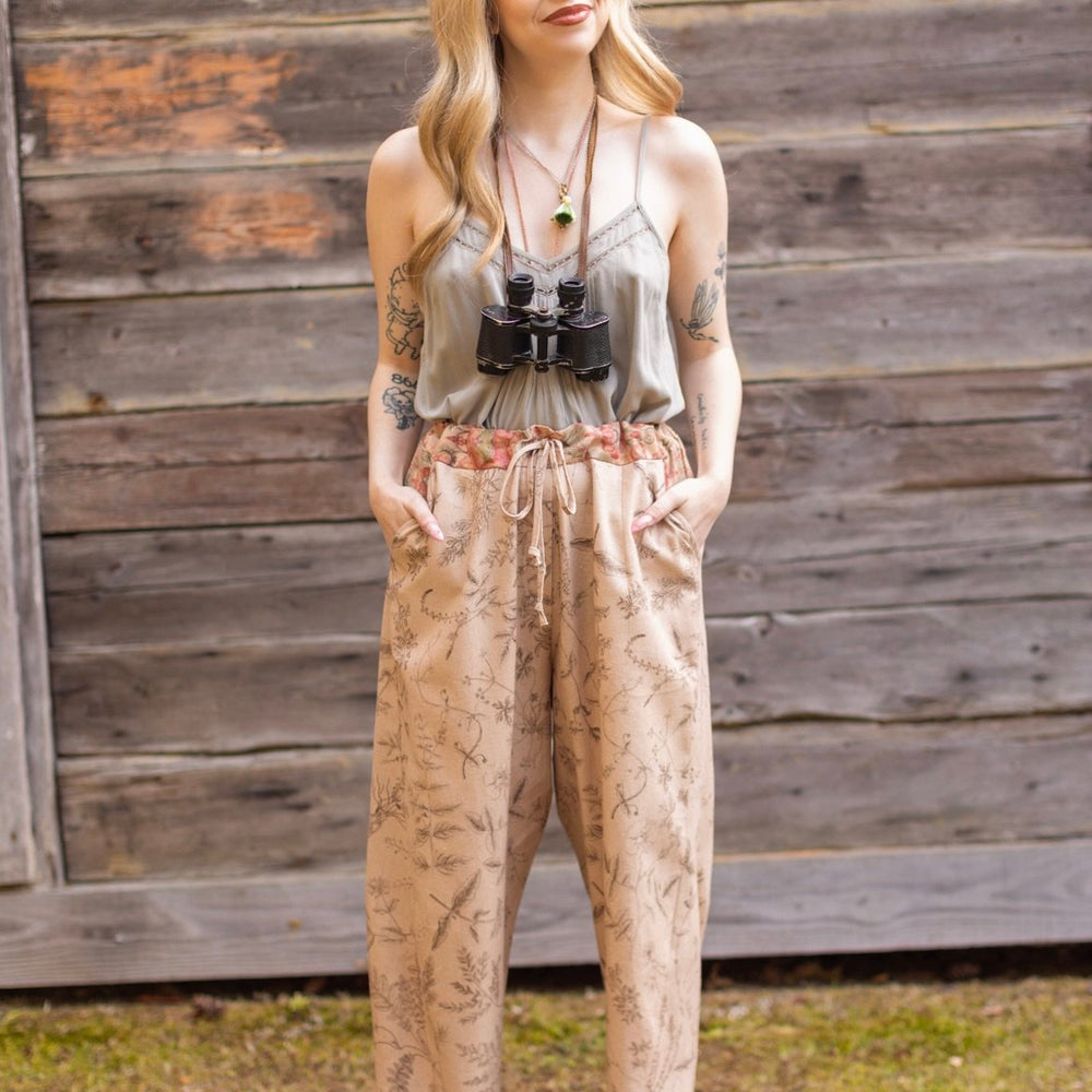 Model wearing artist pants in oat featuring reimagined vintage 1846 map of a woman’s heart with playful updated place names – Market of Stars
