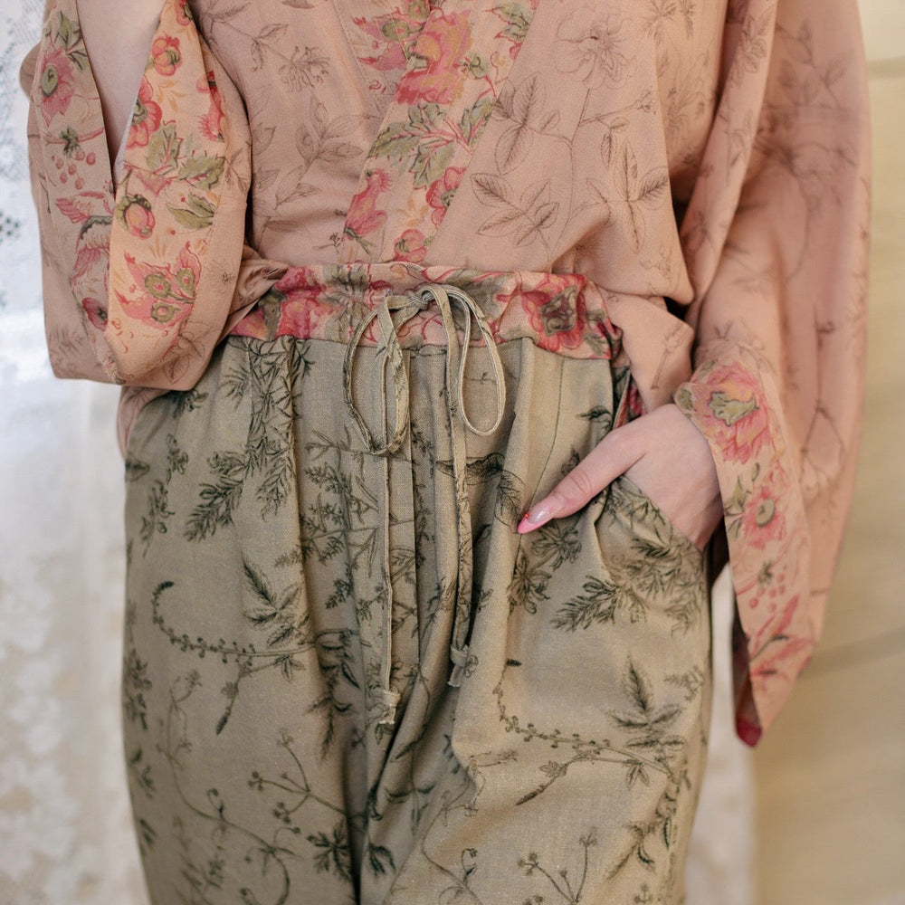 Model wearing artist pants in sage featuring reimagined vintage 1846 map of a woman’s heart with playful updated place names – Market of Stars