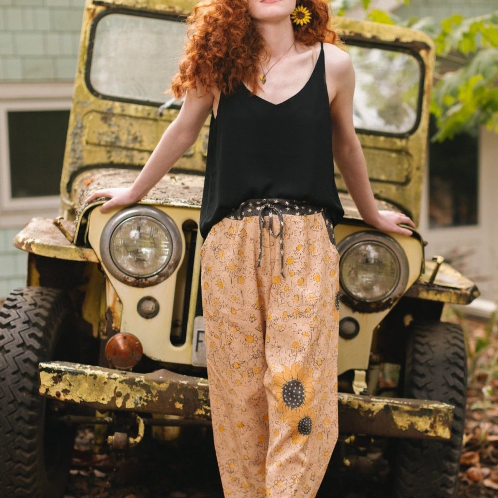 Model wearing the Milk & Honey Artist Pants featuring playful 1904 Brooklyn poster art and antique woodcut star and floral details in vintage-inspired tones – Market of Stars.