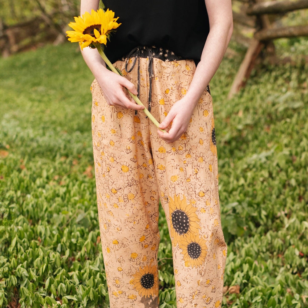 Model wearing the Milk & Honey Artist Pants featuring playful 1904 Brooklyn poster art and antique woodcut star and floral details in vintage-inspired tones – Market of Stars.