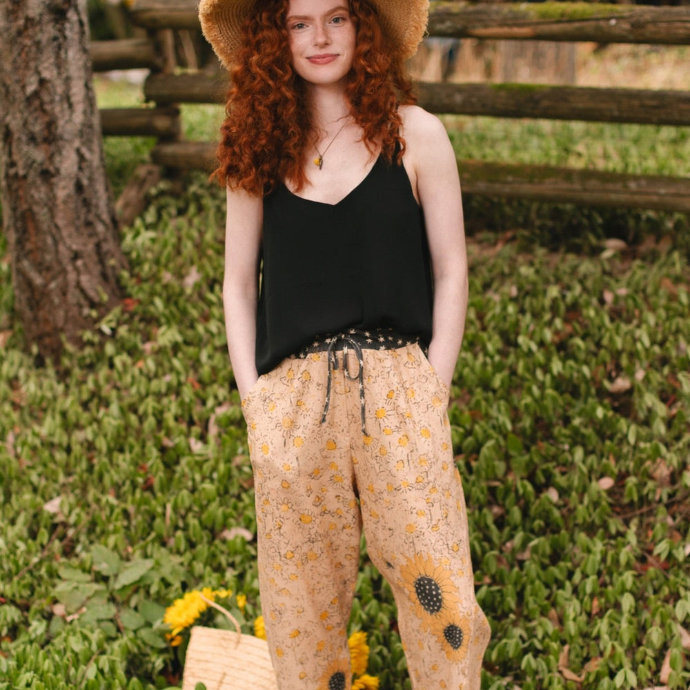 
                  
                    Model wearing the Milk & Honey Artist Pants featuring playful 1904 Brooklyn poster art and antique woodcut star and floral details in vintage-inspired tones – Market of Stars.
                  
                