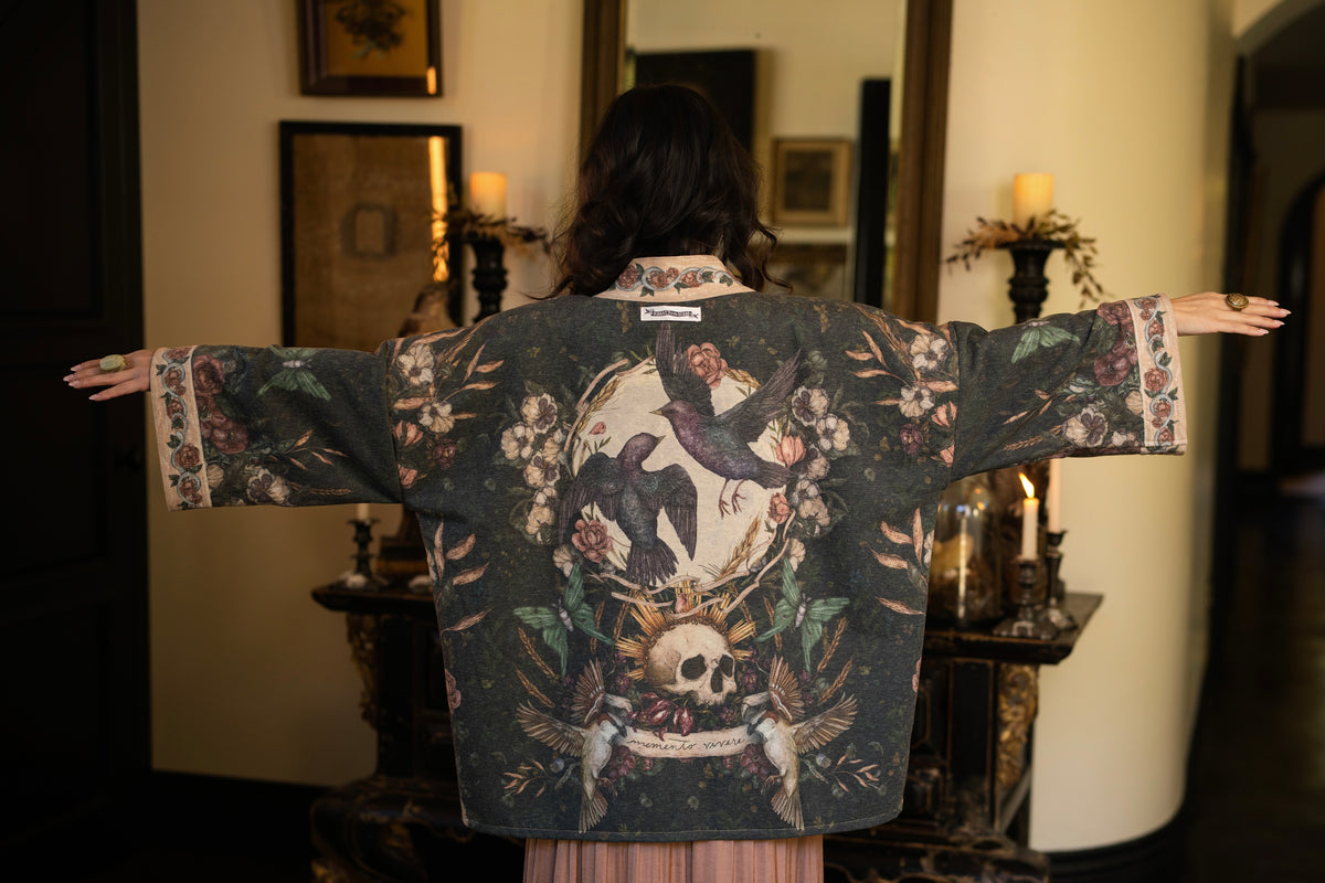 Model wearing a cozy fleece lined cottage cardigan ft. artwork created by Jessica Roux including two starlings beneath a full moon with flowers, butterflies, moths and botanical artwork - Market of Stars