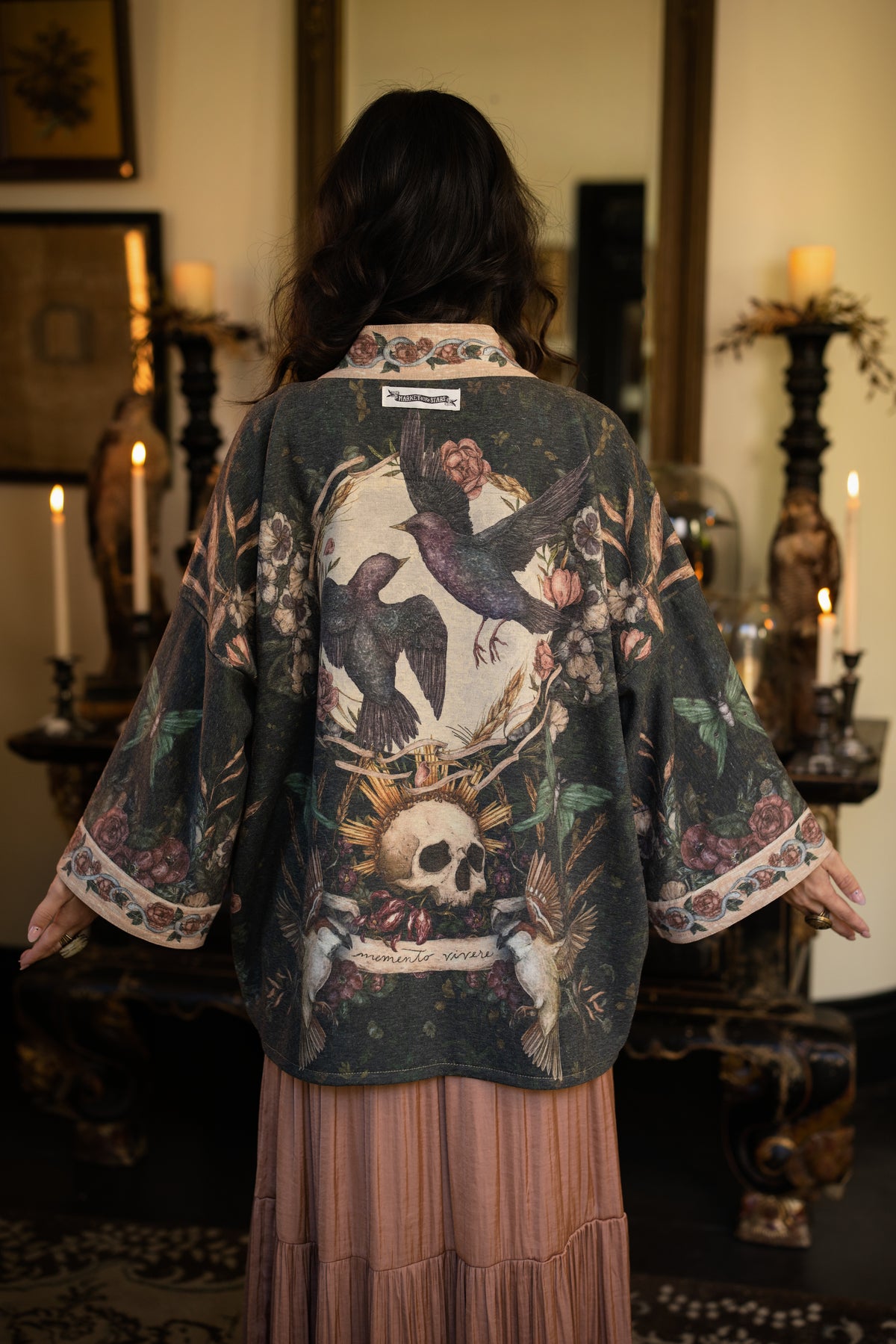 Model wearing a cozy fleece lined cottage cardigan ft. artwork created by Jessica Roux including two starlings beneath a full moon with flowers, butterflies, moths and botanical artwork - Market of Stars