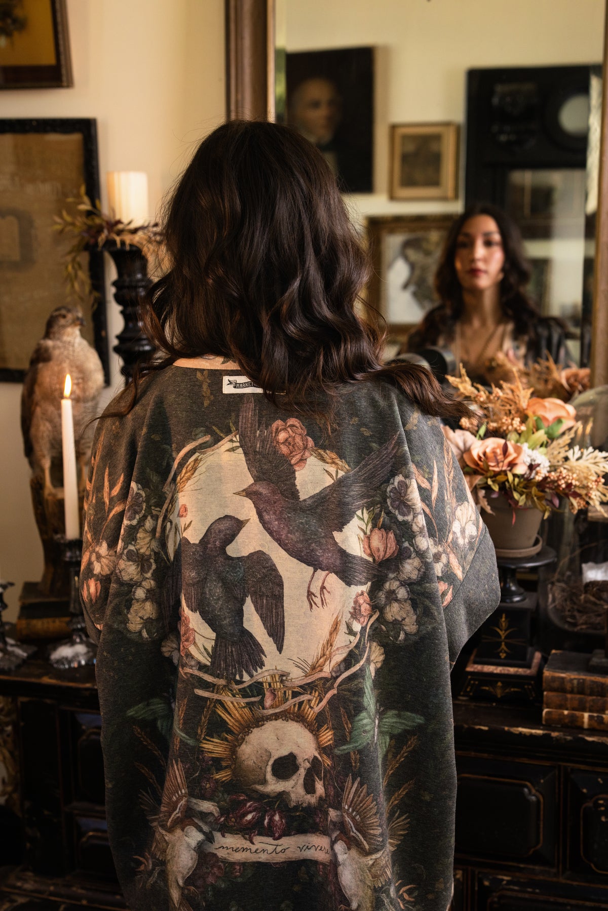 Model wearing a cozy fleece lined cottage cardigan ft. artwork created by Jessica Roux including two starlings beneath a full moon with flowers, butterflies, moths and botanical artwork - Market of Stars