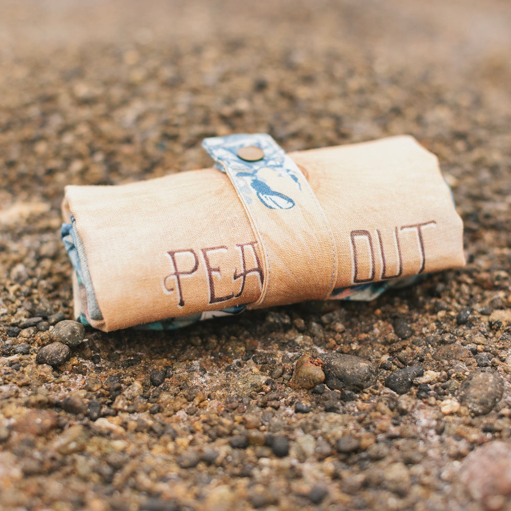 
                  
                    Model wearing our Peace Out tote bag featuring 1800's perfumeur sign with gentle tones of blue & aqua, landscapes, clouds, dove, and peace symbols -Market of Stars.
                  
                