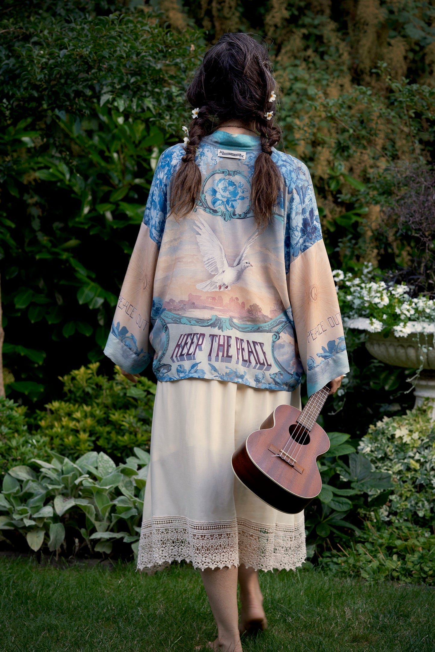 Model wearing our Peace Out Pixie Duster featuring 1800's perfumeur sign with gentle tones of blue & aqua, landscapes, clouds, dove and peace symbols -Market of Stars.