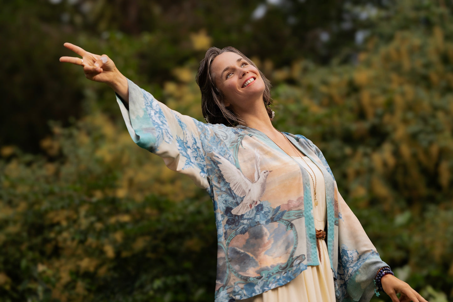 Model wearing our Peace Out Pixie Duster featuring 1800's perfumeur sign with gentle tones of blue & aqua, landscapes, clouds, dove and peace symbols -Market of Stars.