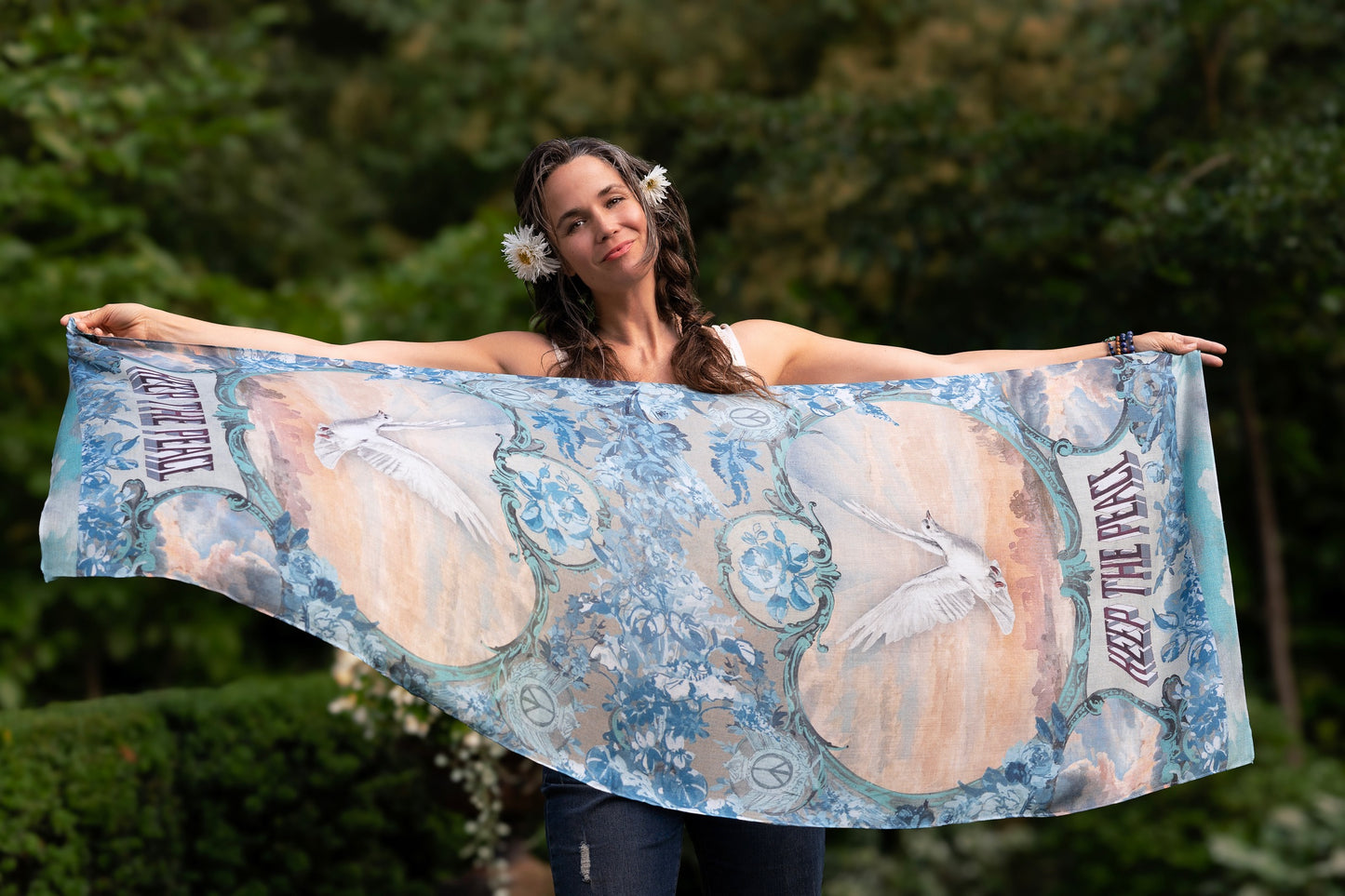 Model wearing our Peace Out scarf featuring 1800's perfumeur sign with gentle tones of blue & aqua, landscapes, clouds, dove, and peace symbols -Market of Stars