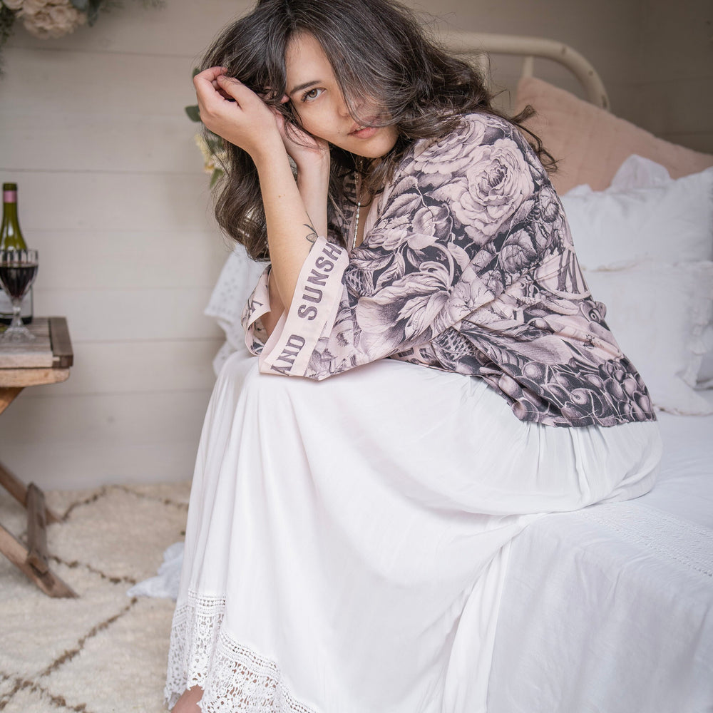 Model wearing Peace, Wine & Sunshine Bohéme Slip Dress featuring botanical collages and playful peace, wine and sunshine lettering on the hem – Market of Stars.