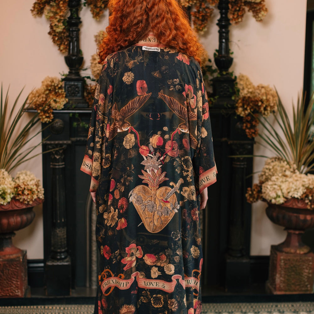 
                  
                    Model wearing a full-length bamboo-viscose duster featuring a collage of antique artwork with romance, loyalty, and old-world beauty - Market of Stars
                  
                