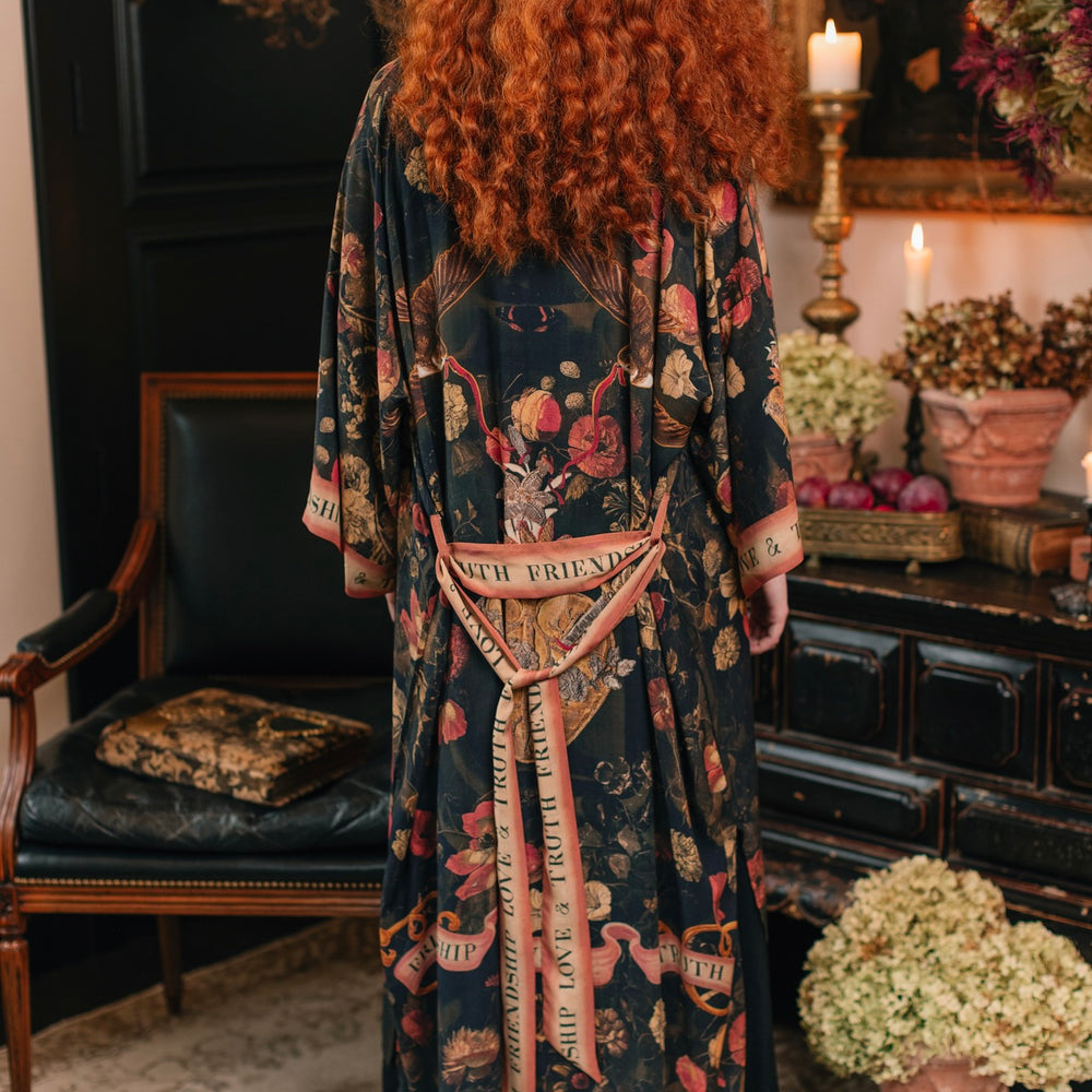 
                  
                    Model wearing a full-length bamboo-viscose duster featuring a collage of antique artwork with romance, loyalty, and old-world beauty - Market of Stars
                  
                
