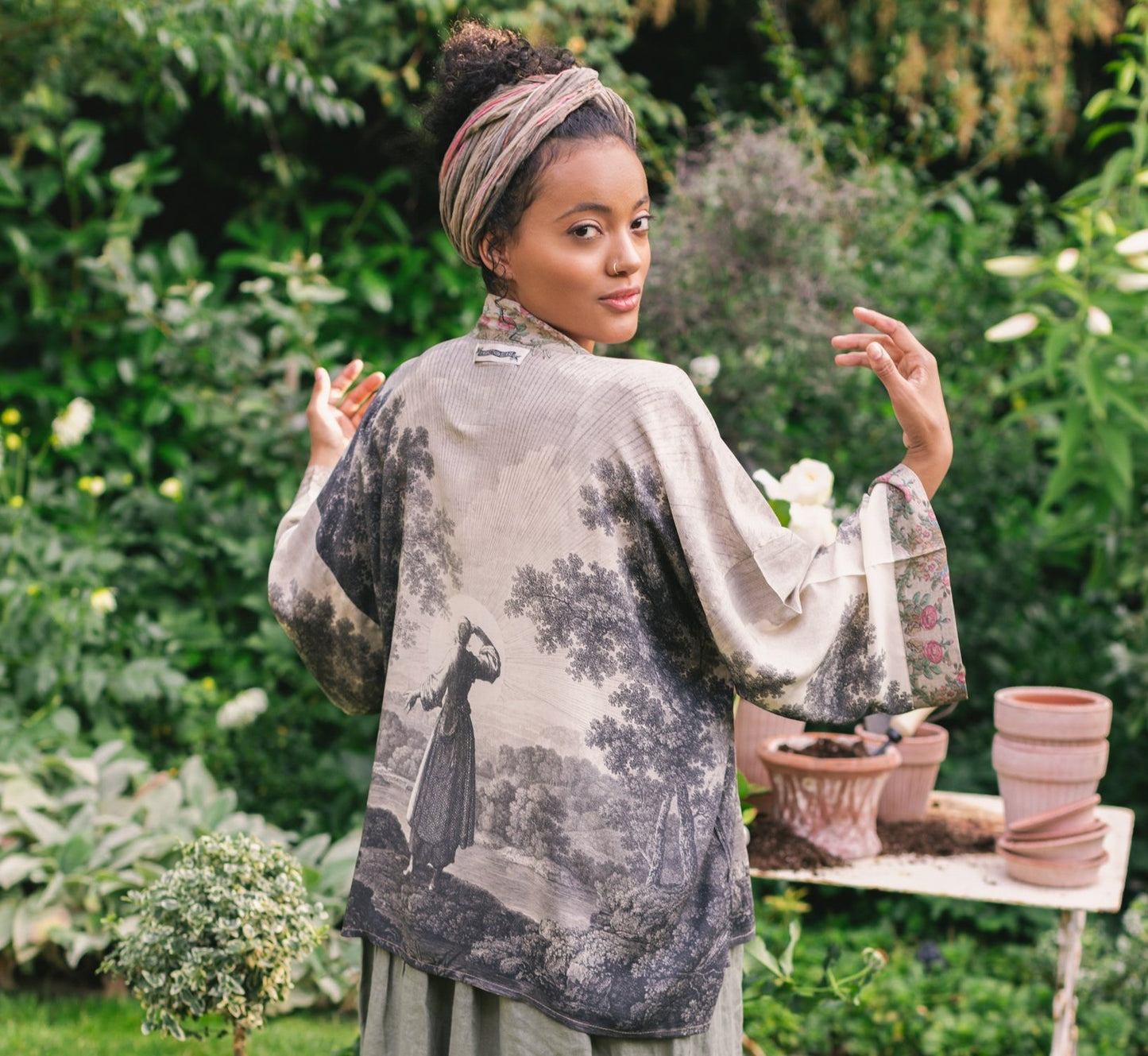 Model wearing our Still I Rise Pixie Duster with empowering message a bold, layered design featuring antique landscape etchings – Market of Stars