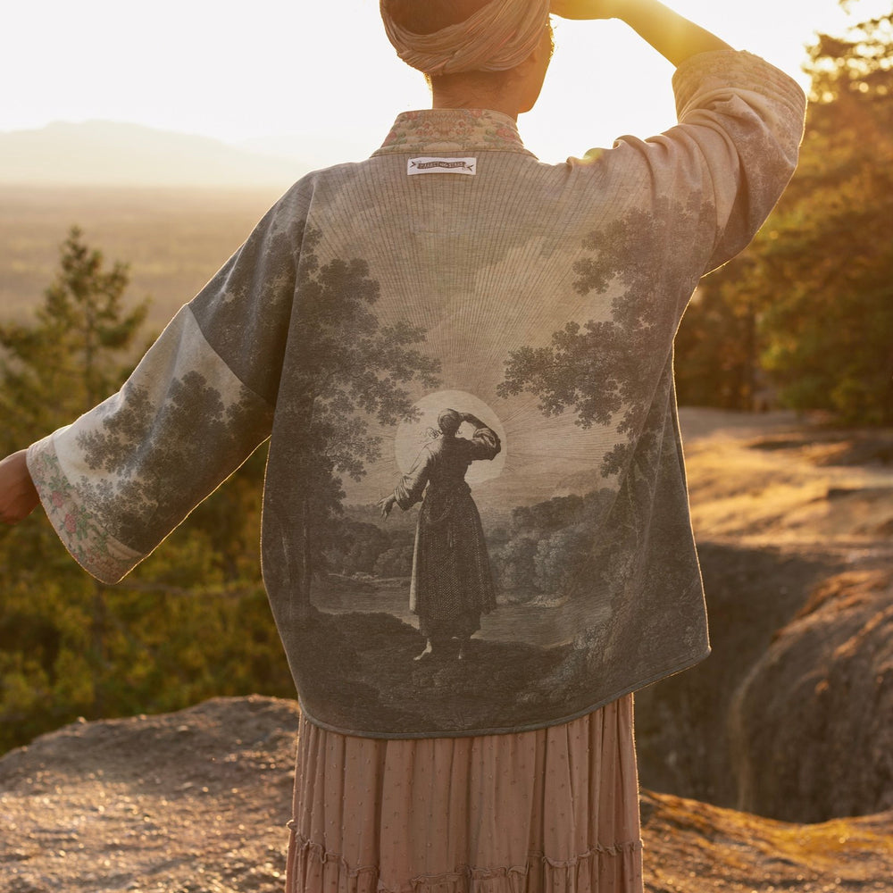 Model wearing the Still I Rise Cottage Cardigan featuring a soft fleece lining and antique landscape etchings in a design inspired by rising strength – Market of Stars