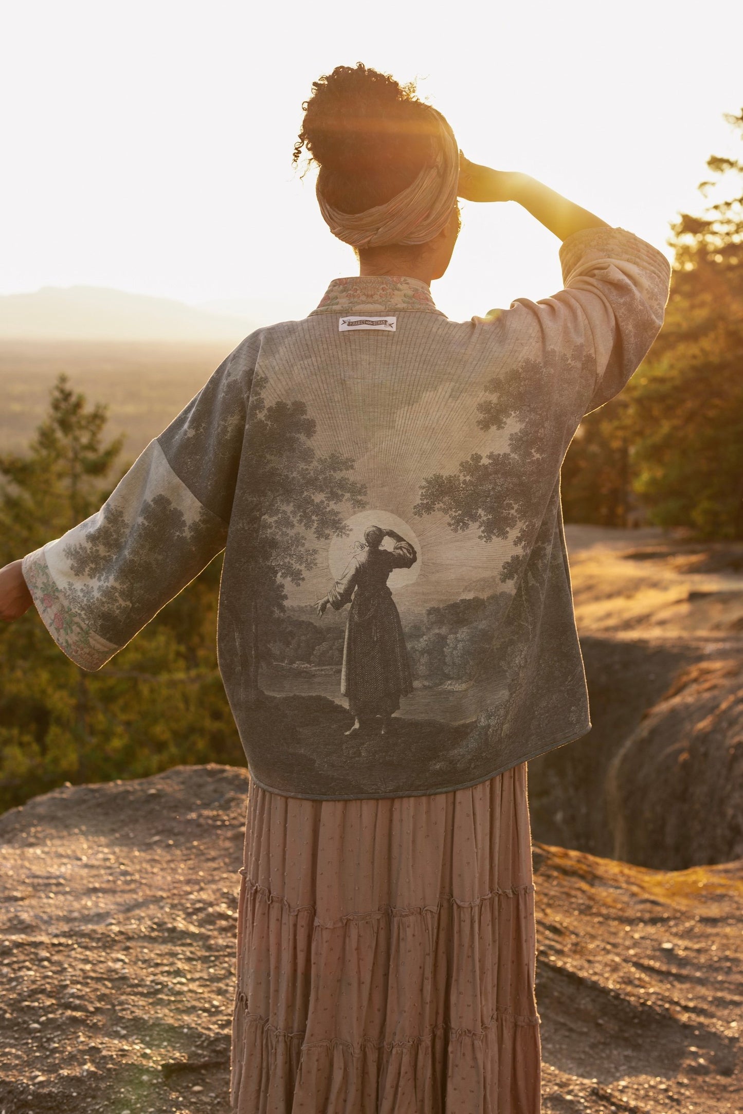 Model wearing the Still I Rise Cottage Cardigan featuring a soft fleece lining and antique landscape etchings in a design inspired by rising strength – Market of Stars