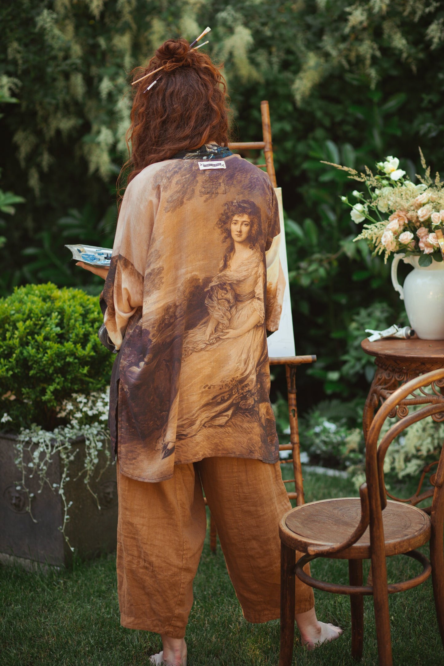 Model wearing The Artist kimono-style duster featuring antique paintings, botanical floral trim, and a radiant golden sun – Market of Stars