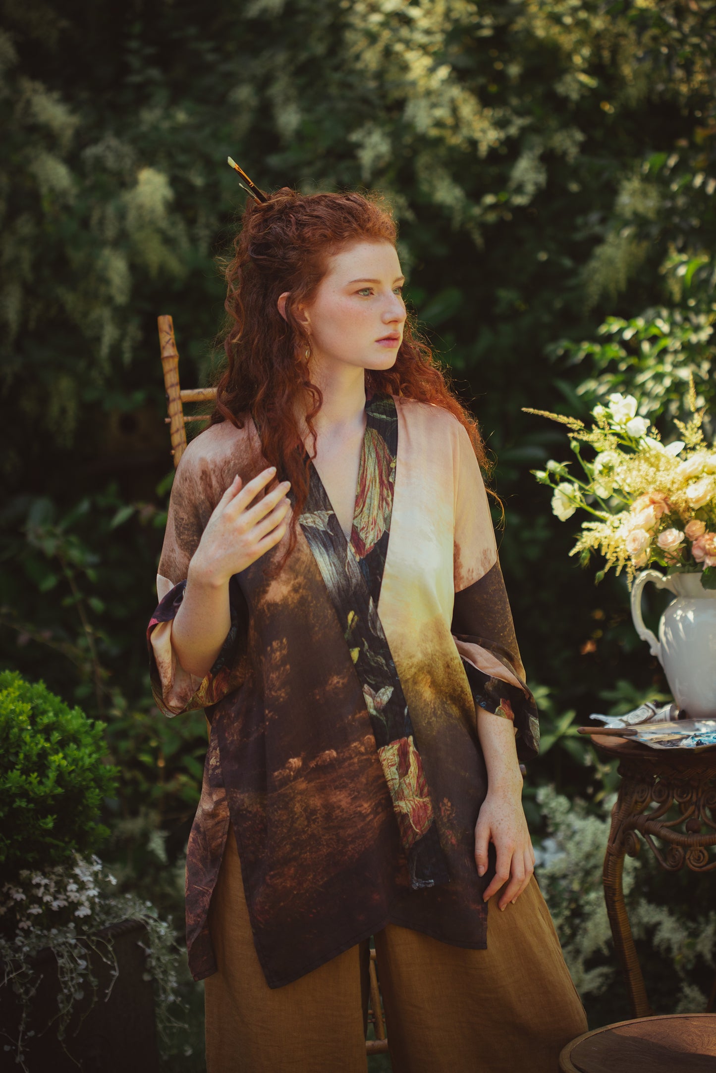 Model wearing The Artist kimono-style duster featuring antique paintings, botanical floral trim, and a radiant golden sun – Market of Stars