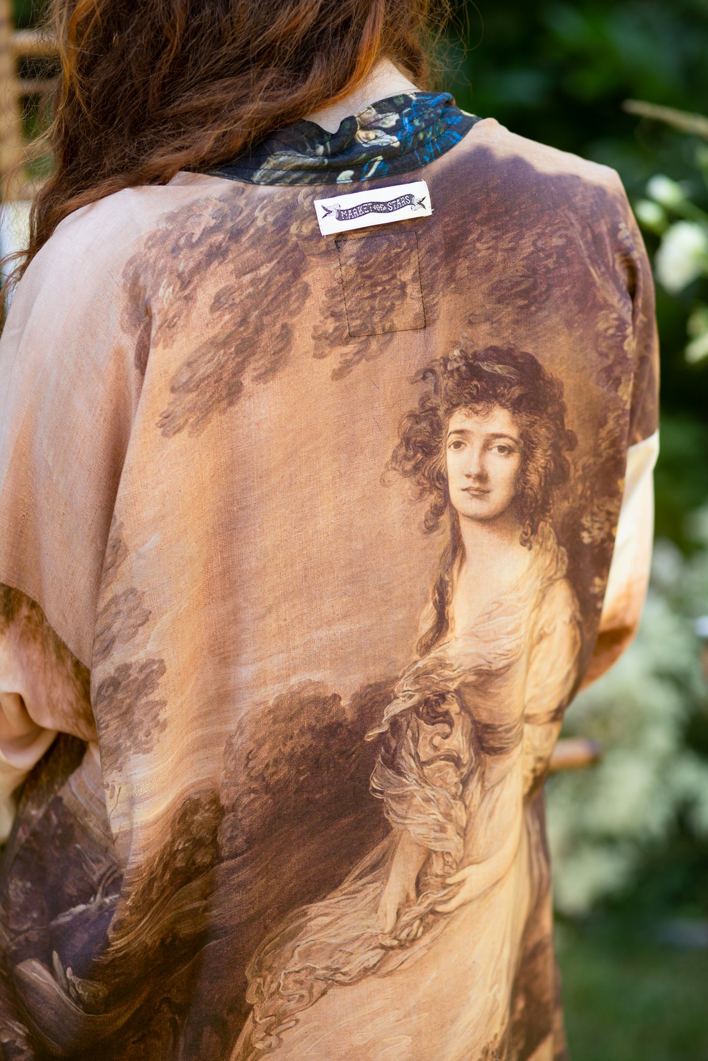 Model wearing The Artist kimono-style duster featuring antique paintings, botanical floral trim, and a radiant golden sun – Market of Stars