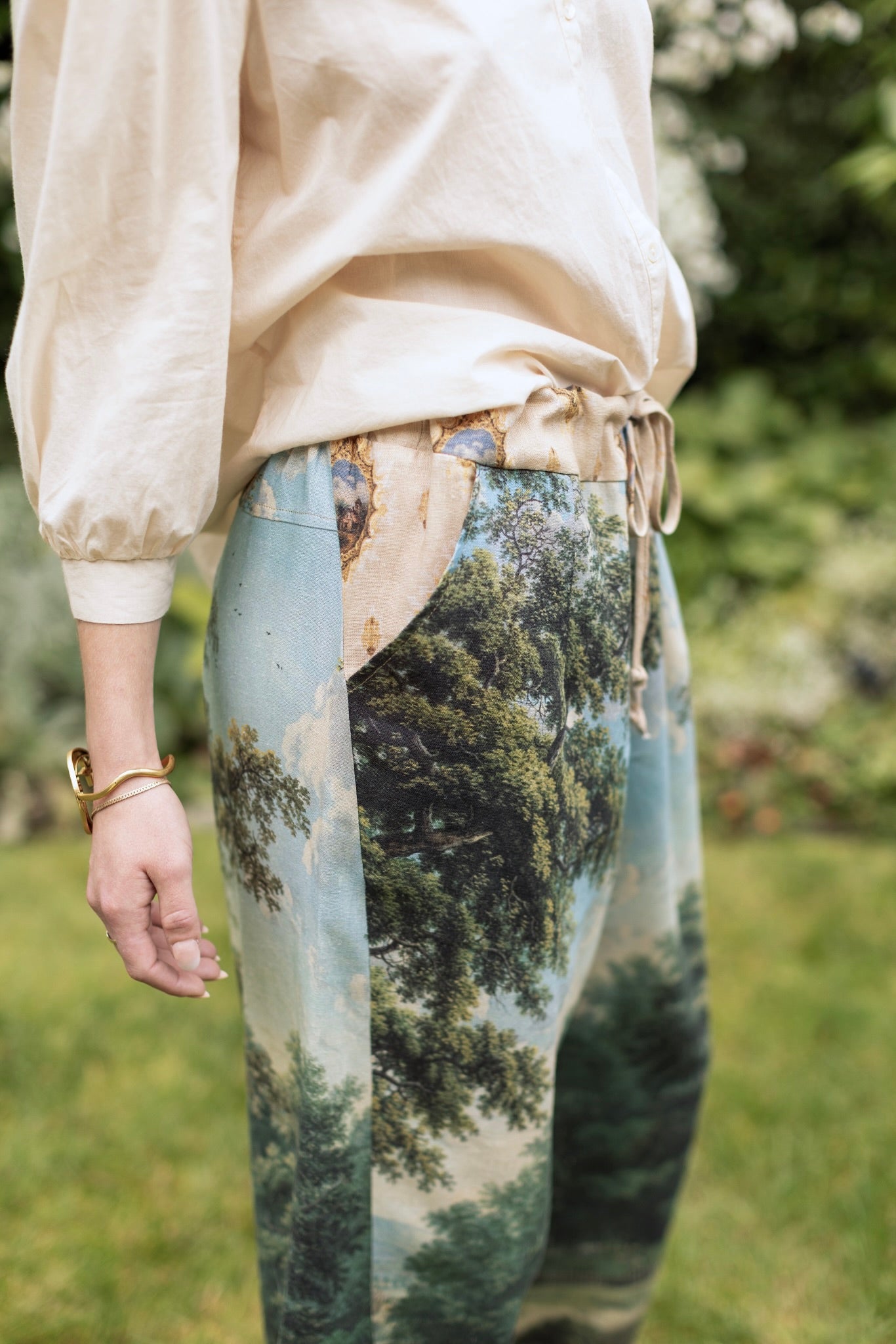 Model wearing a cropped length linen blend pant ft. vintage artwork & unicorn lorn set against a mossy-green landscape — a romantic piece for the modern dreamer - Market of Stars