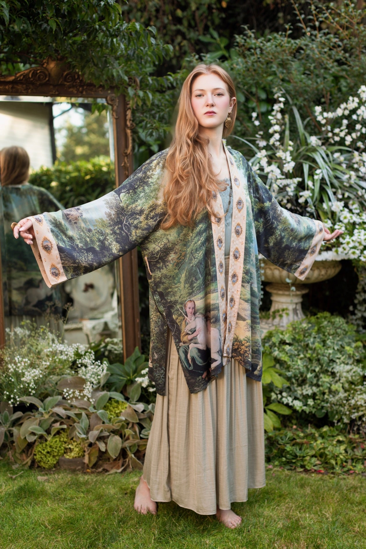 Model wearing a mid-length duster ft. vintage artwork & unicorn lorn set against a mossy-green landscape — a romantic piece for the modern dreamer - Market of Stars