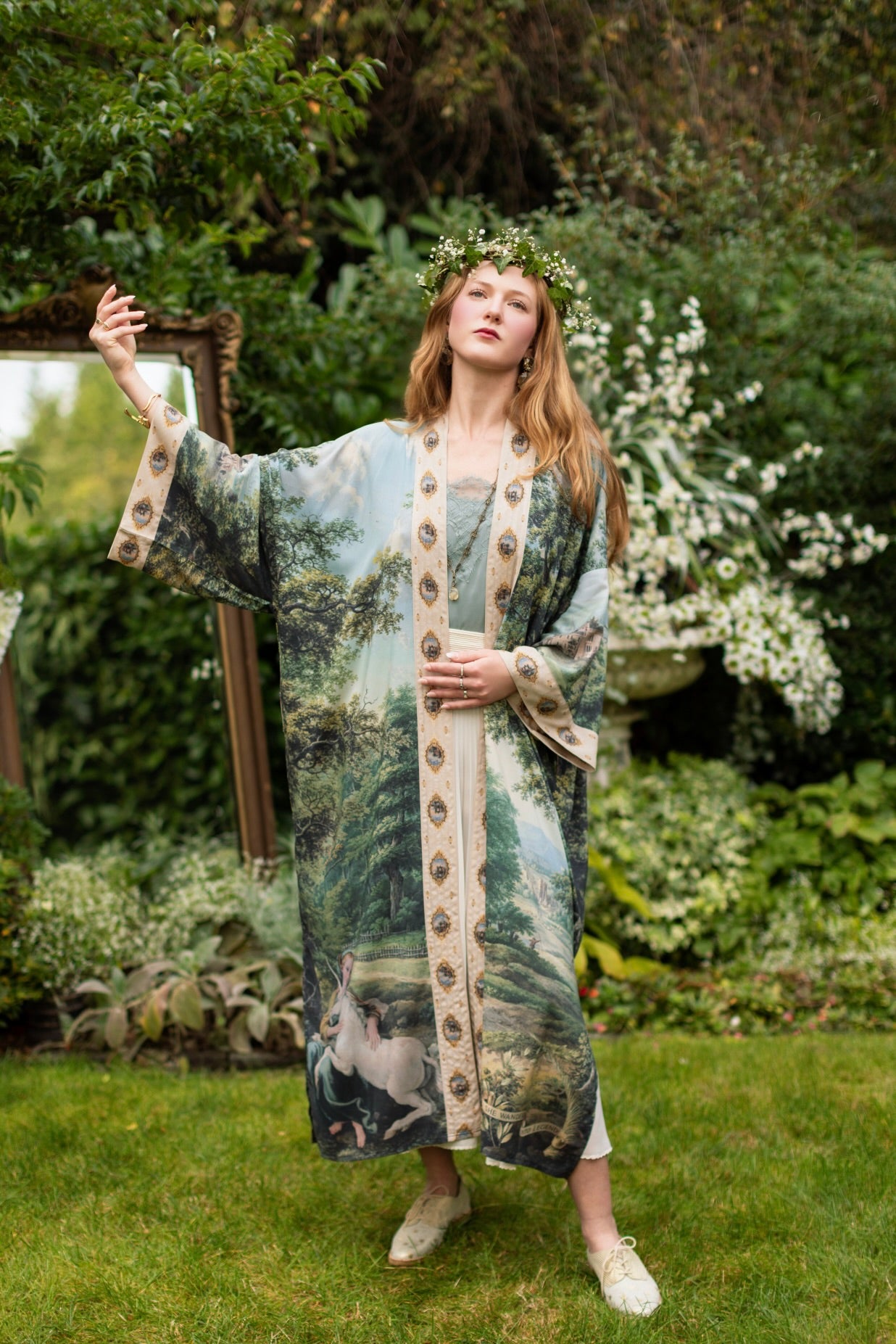 Model wearing a full-length duster ft. vintage artwork & unicorn lorn set against a mossy-green landscape — a romantic piece for the modern dreamer - Market of Stars