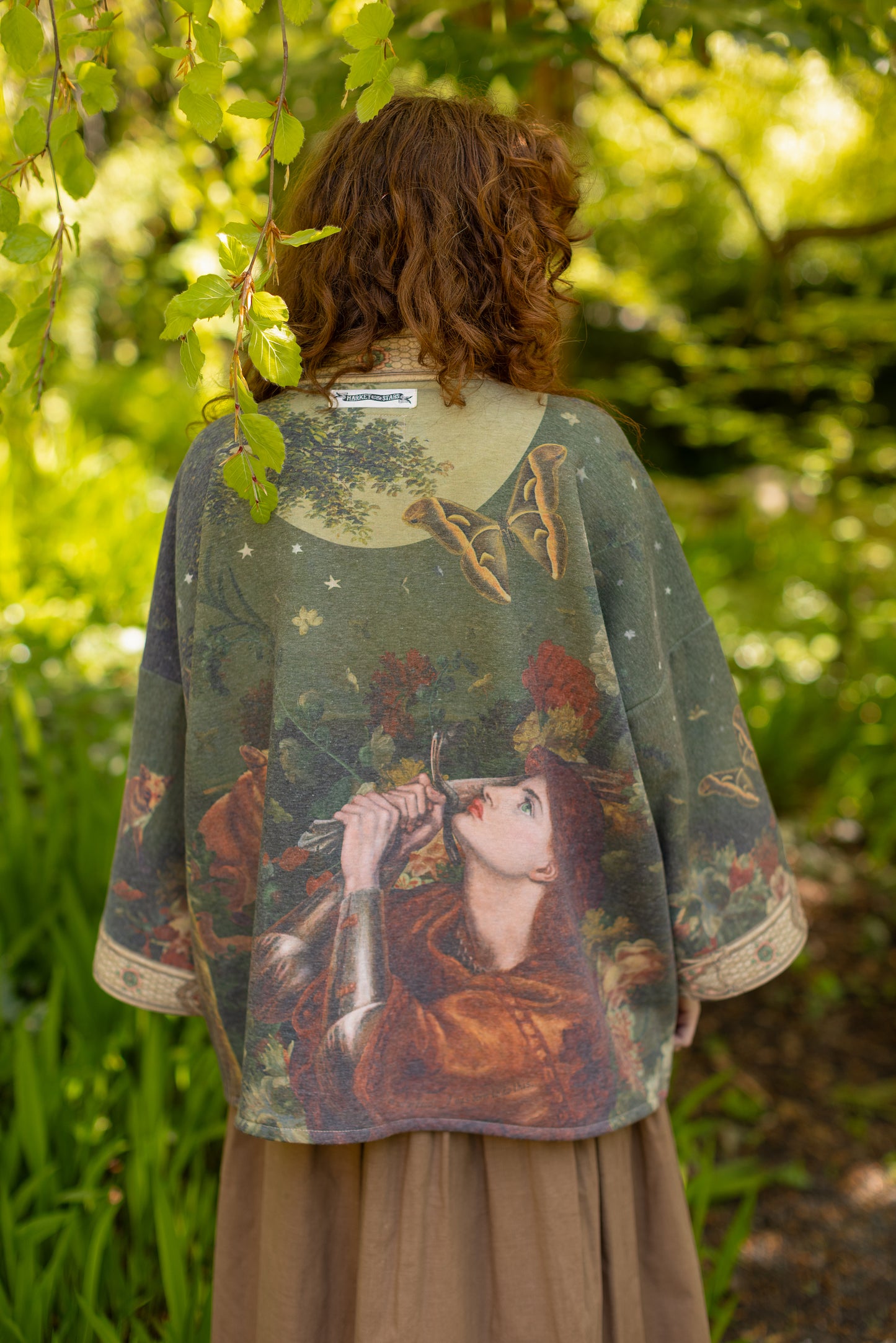 Model wearing a cozy cardigan lined with fleece featuring florals from centuries-old paintings and Rosetti’s iconic portrait of Joan of Arc - Market of Stars