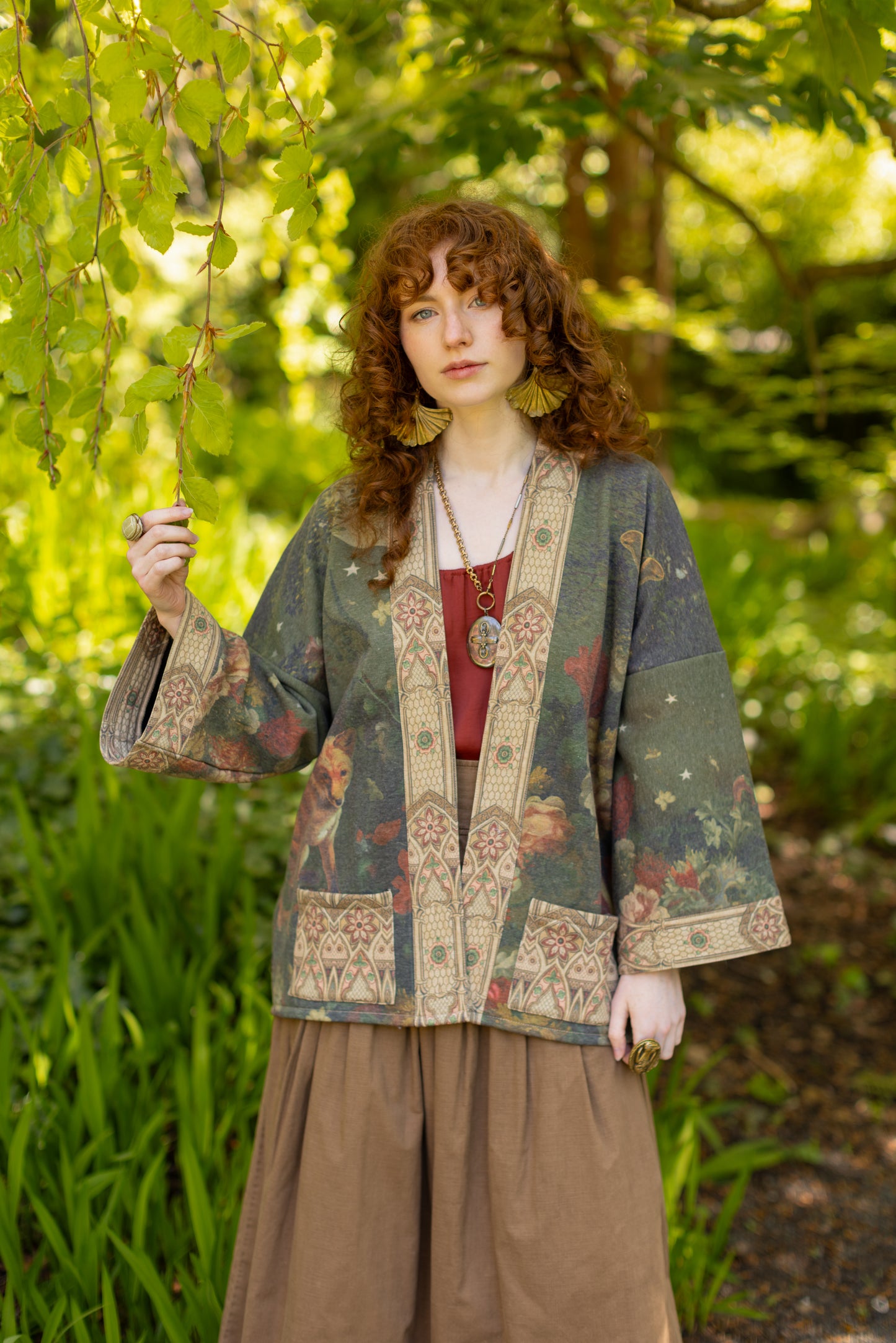 Model wearing a cozy cardigan lined with fleece featuring florals from centuries-old paintings and Rosetti’s iconic portrait of Joan of Arc - Market of Stars