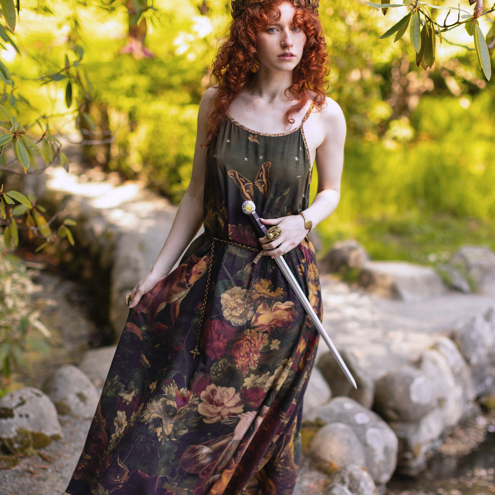 
                  
                    Model wearing a maxi-length bamboo-viscose slip dress featuring florals from centuries-old paintings and Rosetti’s iconic portrait of Joan of Arc - Market of Stars
                  
                