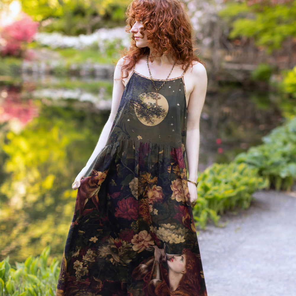 
                  
                    Model wearing a maxi-length bamboo-viscose slip dress featuring florals from centuries-old paintings and Rosetti’s iconic portrait of Joan of Arc - Market of Stars
                  
                